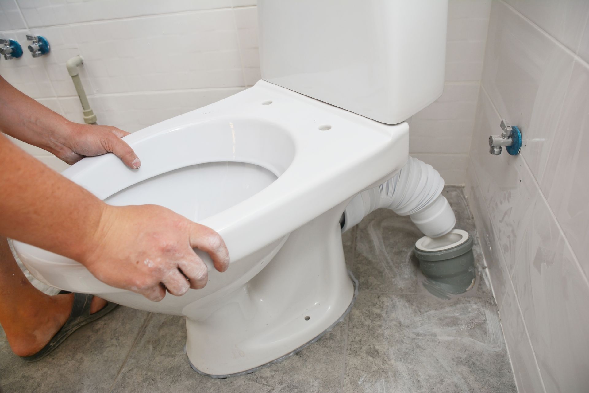 A handyman hands skillfully installing a flush toilet bowl in a bathroom.