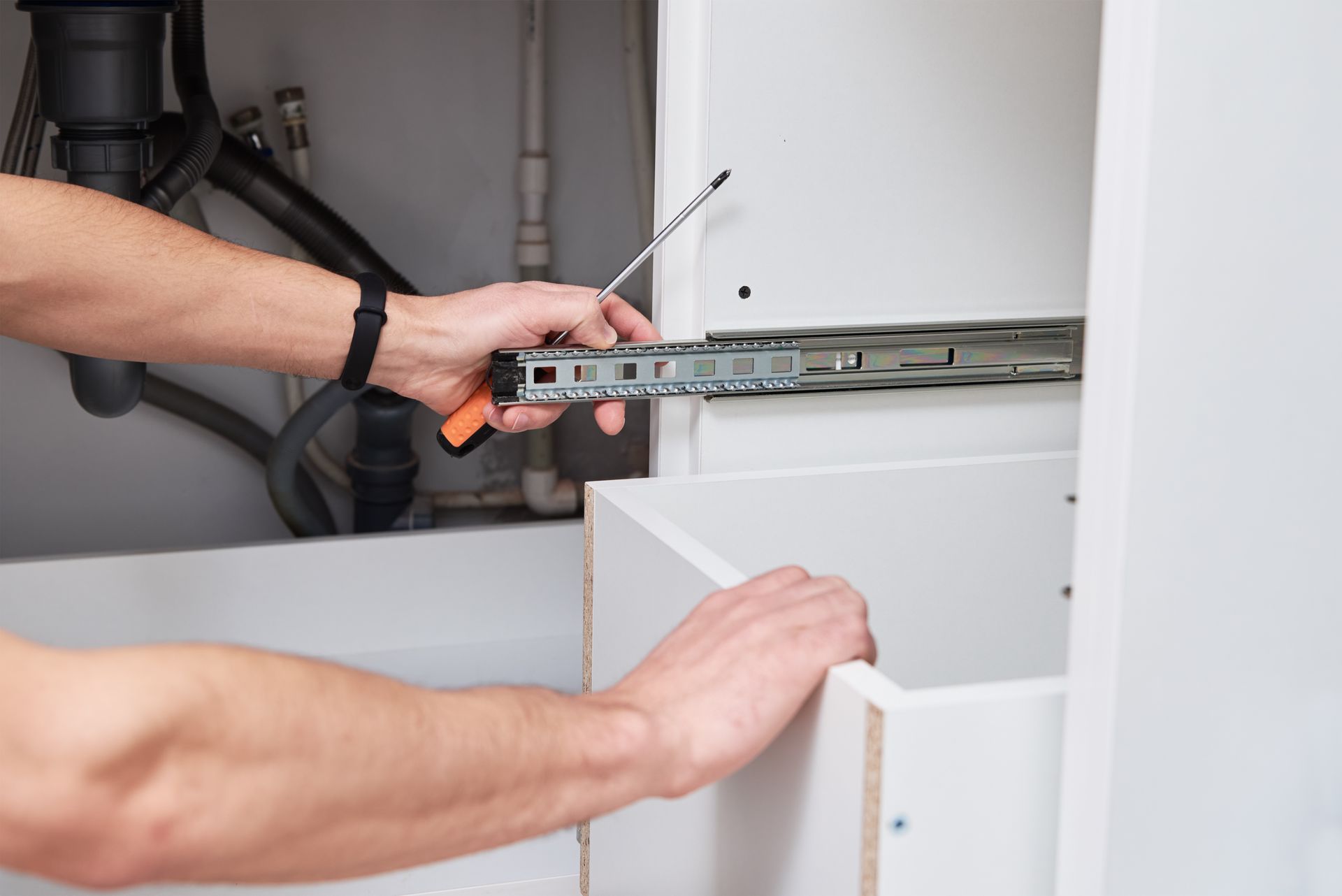 A male carpenter carefully installing a shelf inside a kitchen cabinet, ensuring a perfect fit and stability.