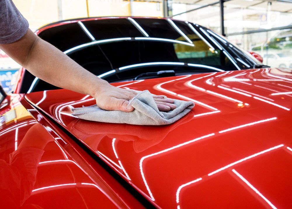 A Person Is Cleaning A Red Car With A Cloth — Shine Your Ride In Yass, NSW