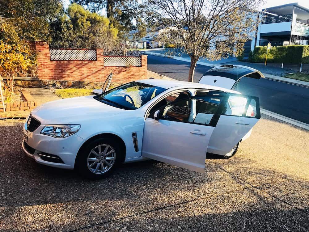 A White Car Is Parked On The Side Of The Road With Its Doors Open — Shine Your Ride In Karabar, NSW