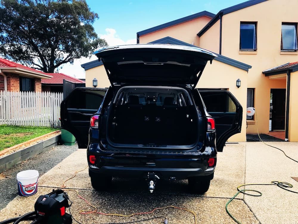 A Black Suv With The Trunk Open Is Parked In Front Of A House — Shine Your Ride In Queanbeyan, NSW