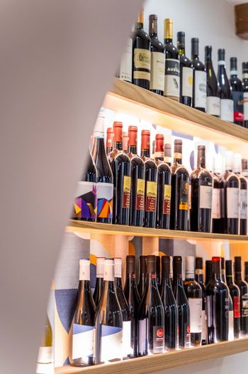 Scaffali pieni di bottiglie di vino assortite in una vetrina di un negozio.