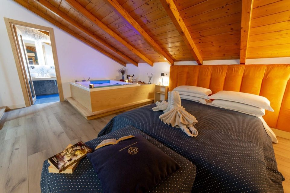 Accogliente camera da letto in stile loft con soffitto in legno, testiera arancione e letto sormontato da asciugamani piegati.