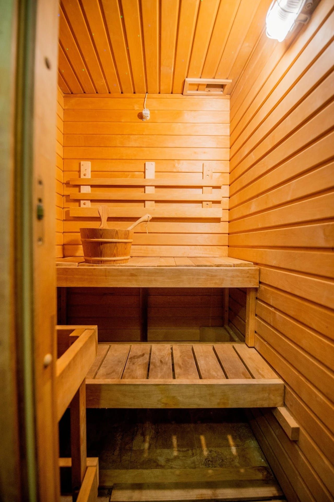 Sauna rivestita in legno con panche in legno e illuminazione calda.