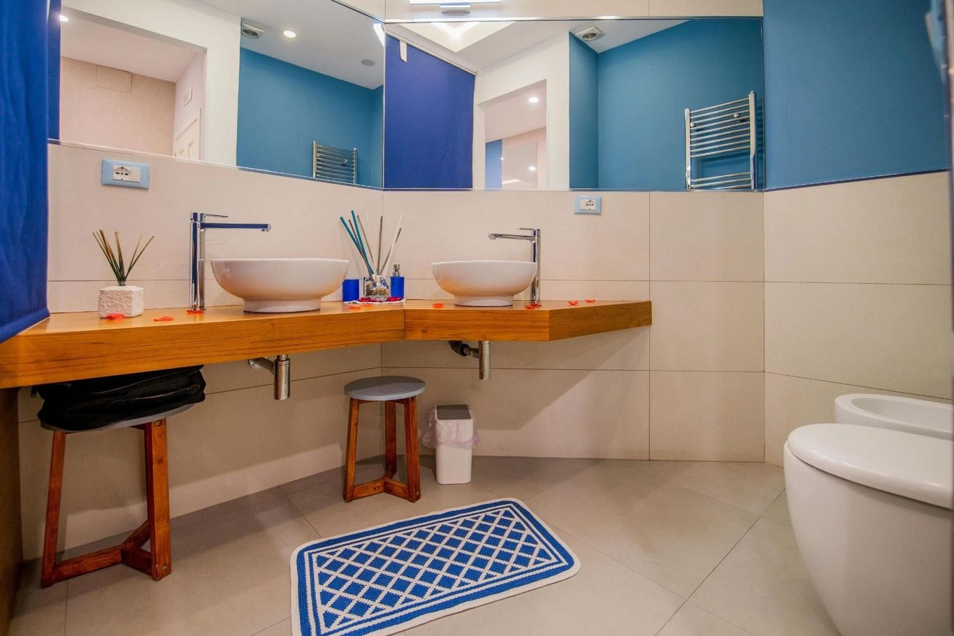 Bagno moderno con doppio lavabo, piano in legno, dettagli blu e WC sulla destra.