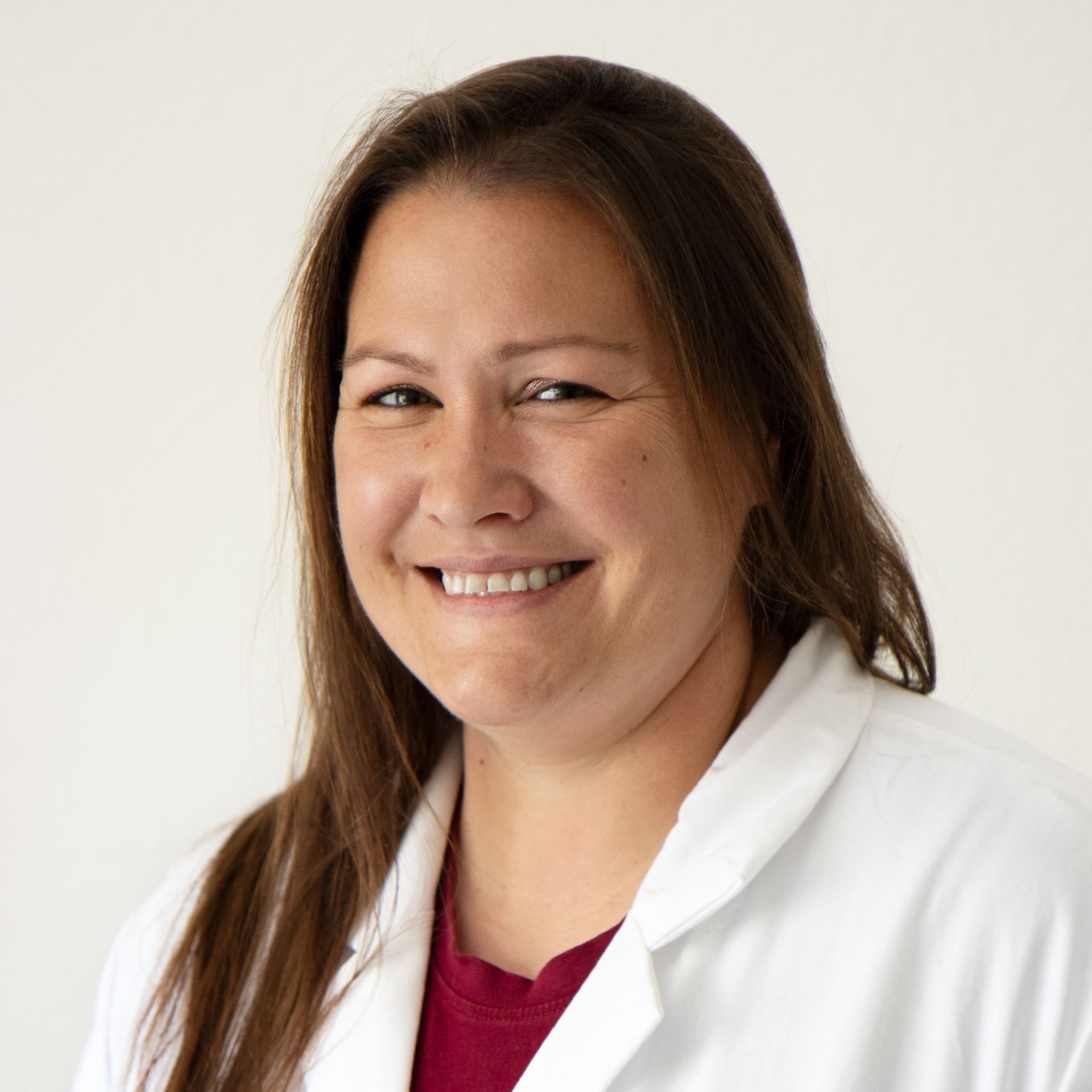 Eine Frau in einem weißen Laborkittel lächelt in die Kamera.