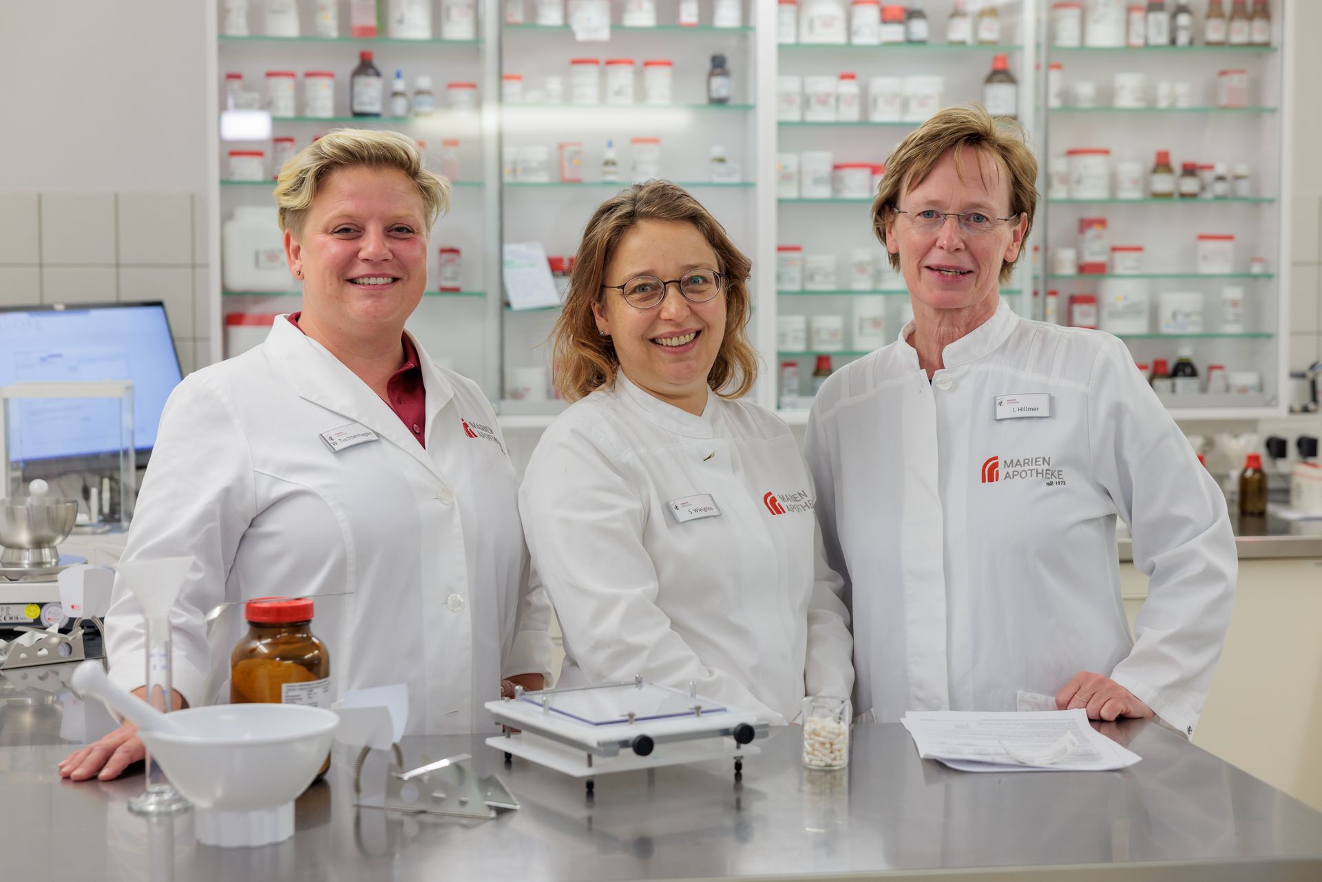 Drei Apothekerinnen posieren in einer Apotheke für ein Foto.