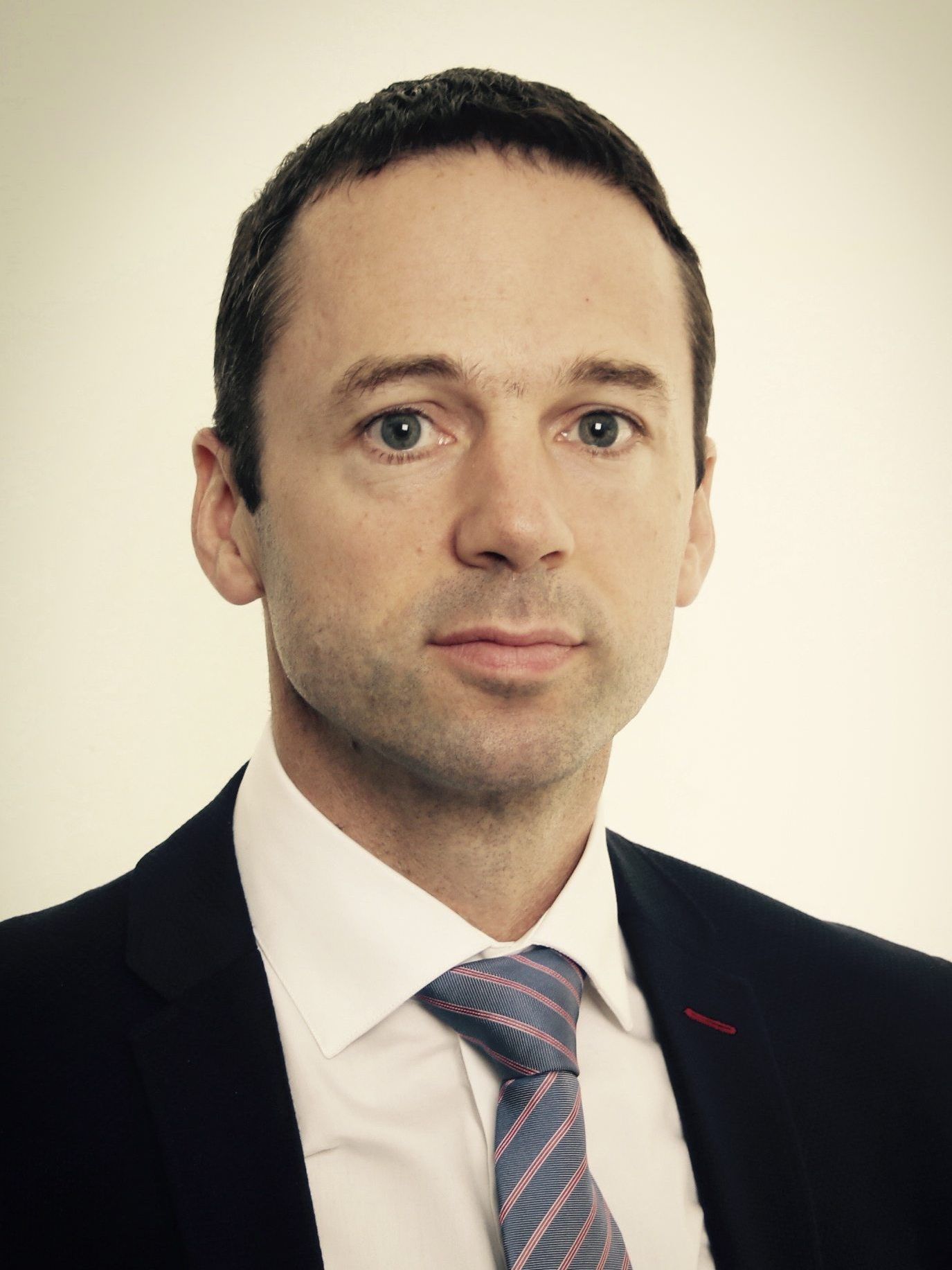 A man in a suit and tie is looking at the camera