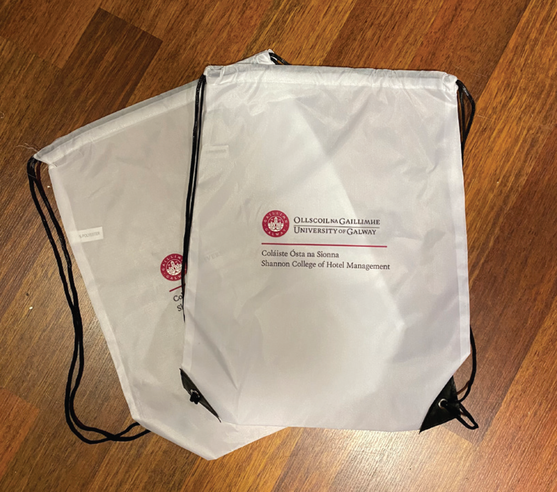 Three white drawstring bags are sitting on a wooden floor
