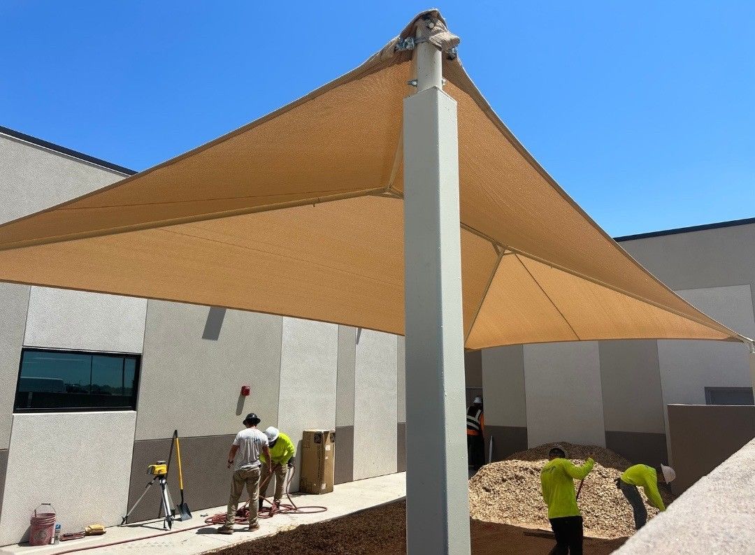A group of men are working under an umbrella in front of a building