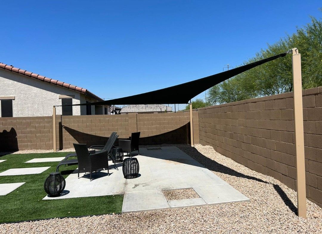 A patio with chairs and a shade sail in the backyard