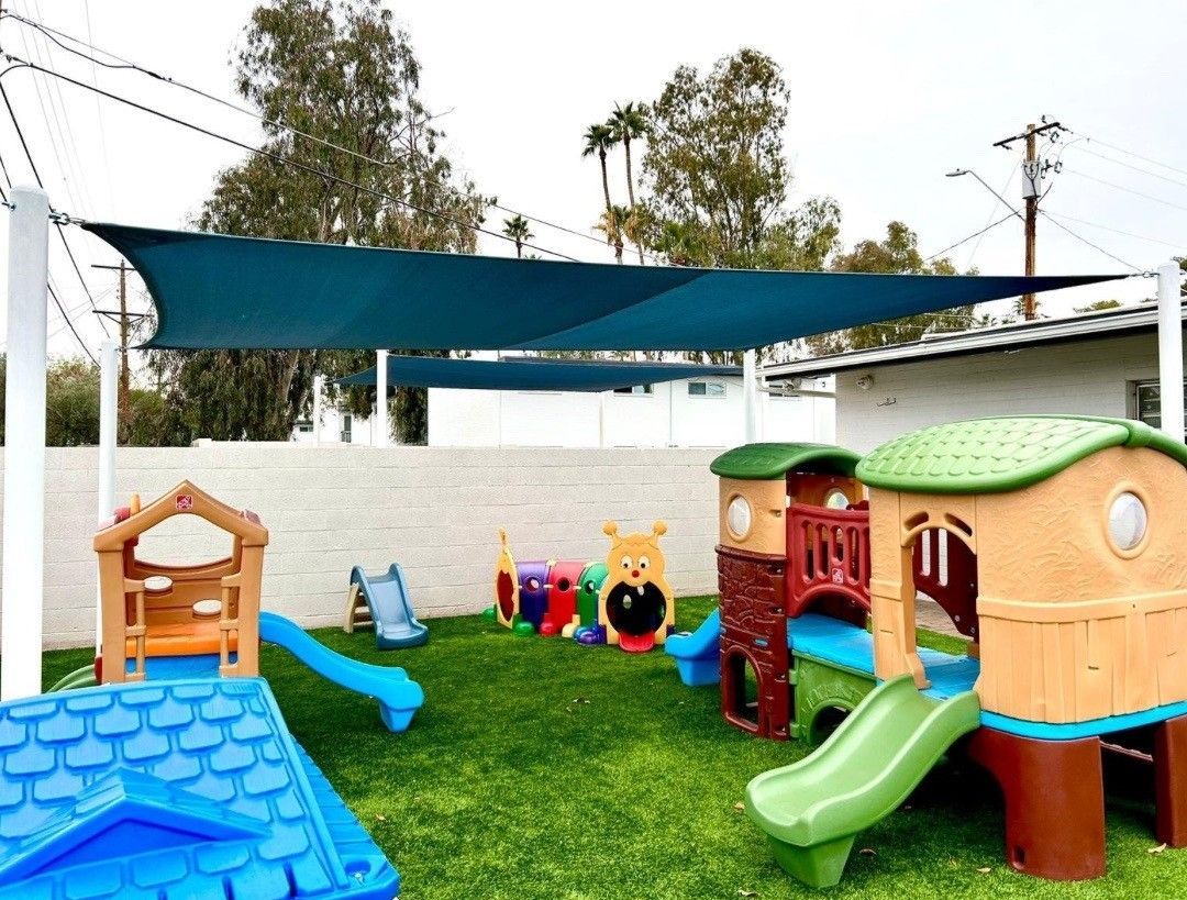 A playground with a slide , house , and umbrella.