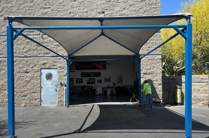 A man is standing under a canopy in front of a brick building
