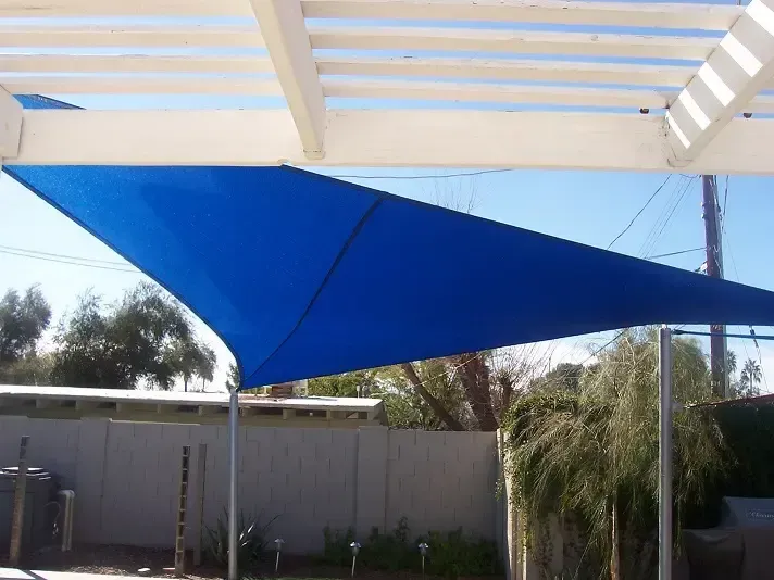 A blue umbrella is sitting under a white pergola