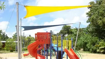 A playground with a slide and a yellow shade sail.