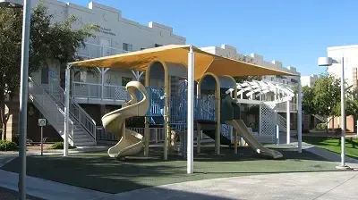 A playground with a slide and stairs in front of a building