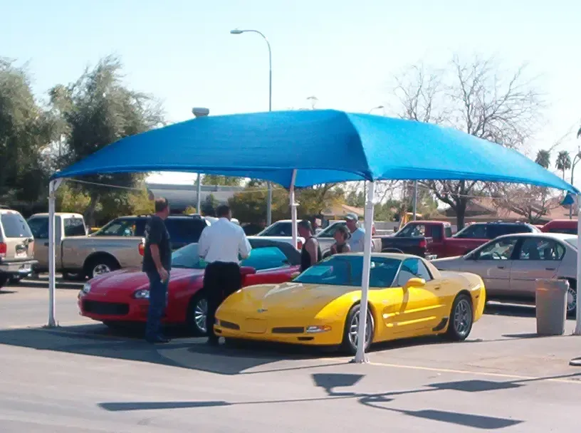 A yellow sports car is parked under a blue umbrella