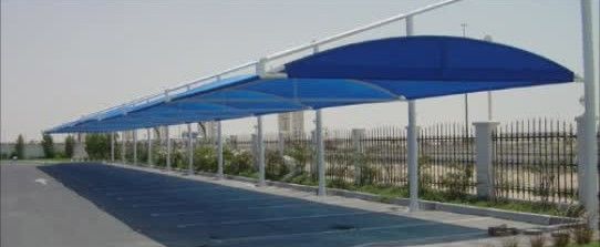 A row of blue umbrellas are lined up on the side of a road.