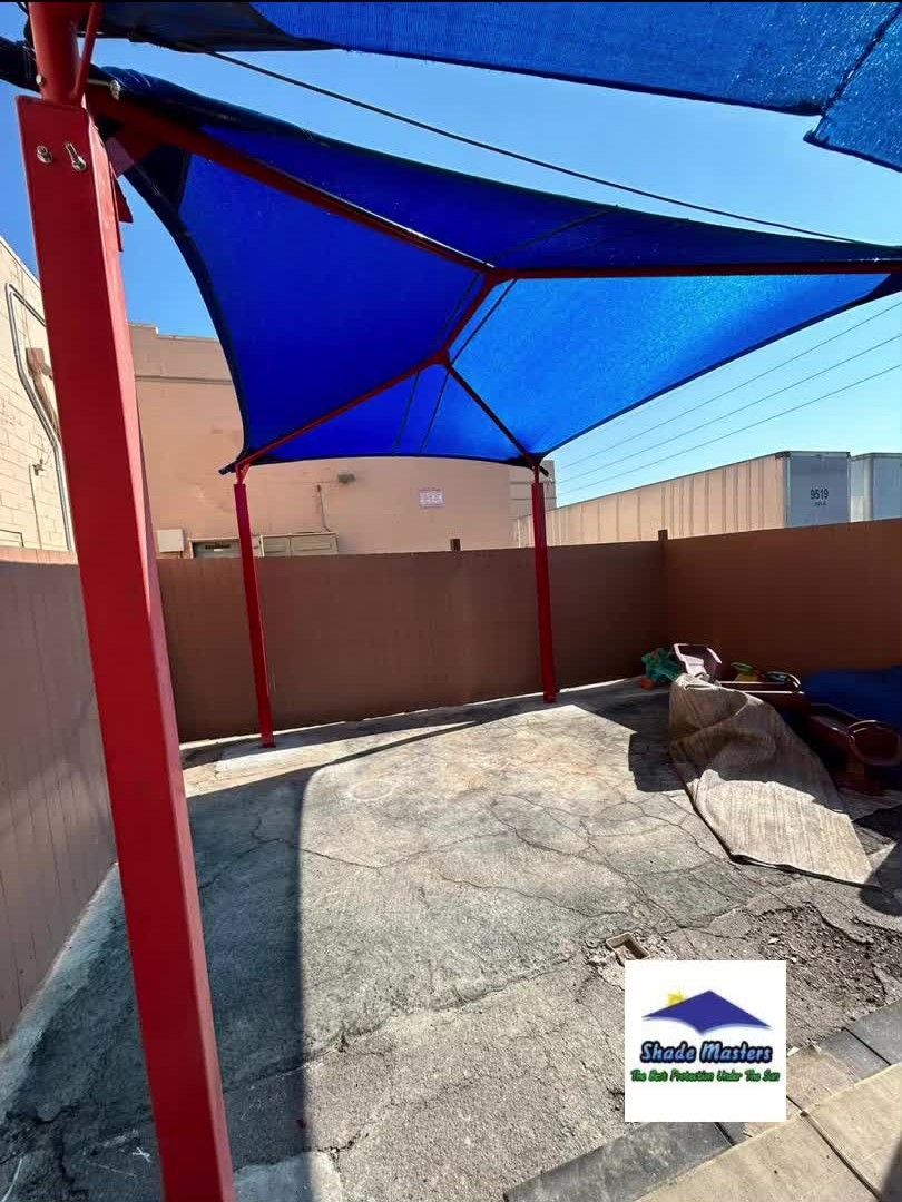 A blue umbrella with a red pole in a backyard