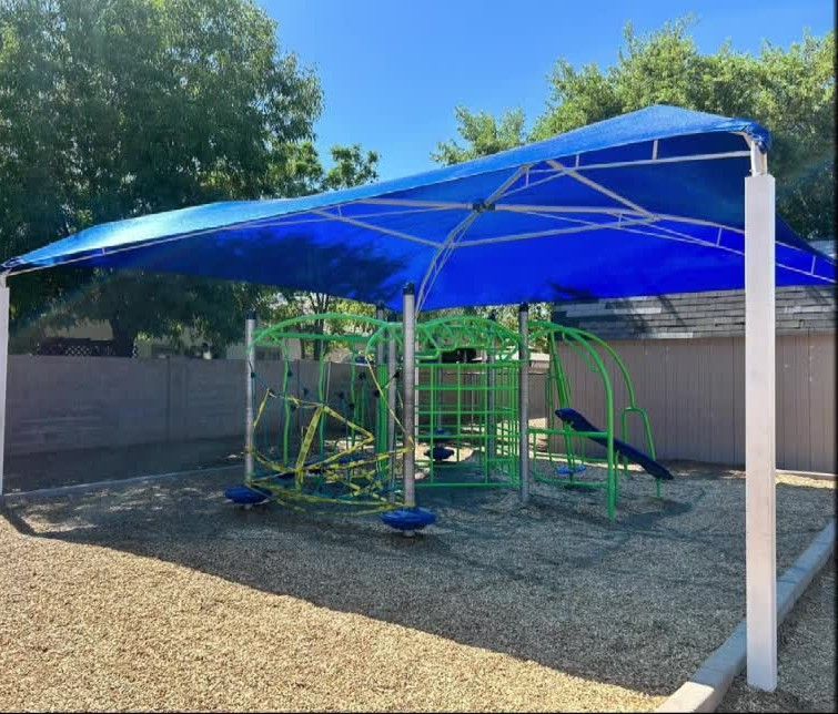 A playground with a blue umbrella over it