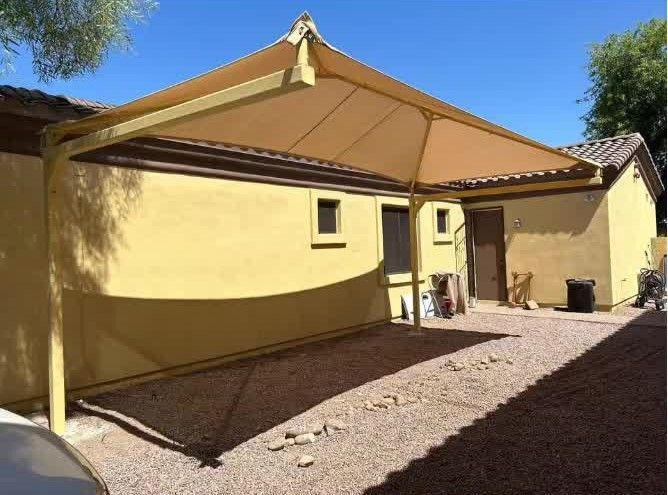 A yellow building with a shade structure in front of it