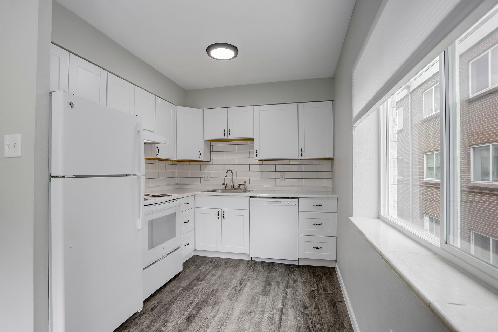 a kitchen with white cabinets and appliances and a large window