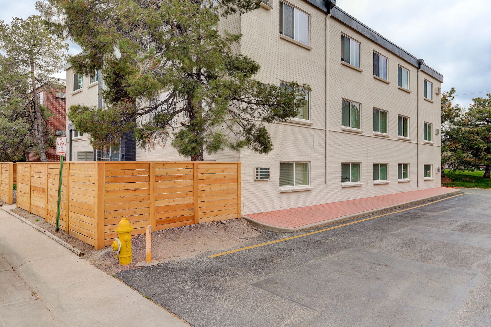 a white building with a wooden fence around it and a fire hydrant in front of it .