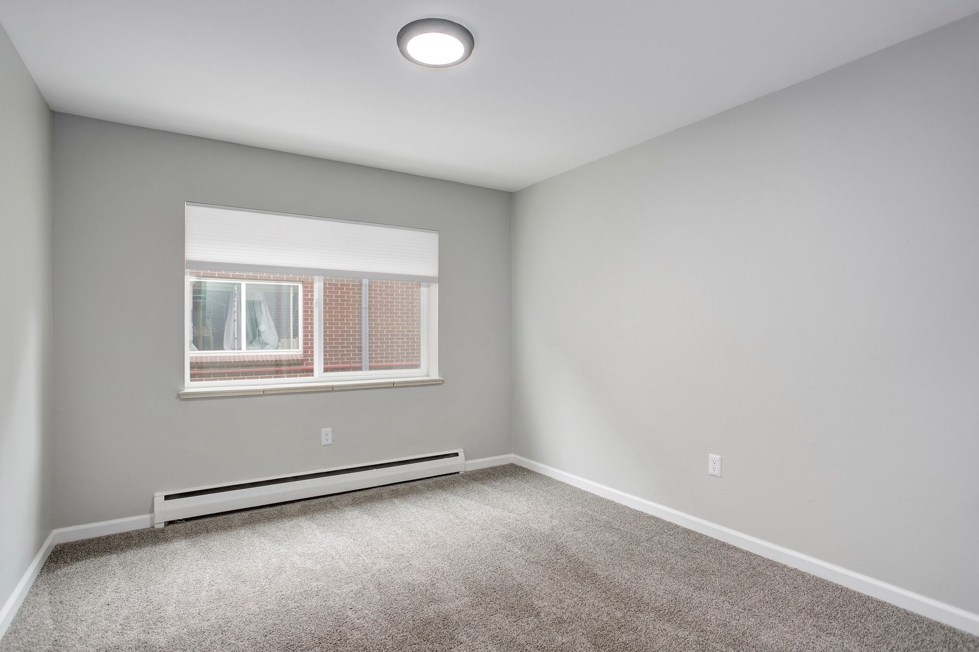 an empty bedroom with a window and a carpeted floor .
