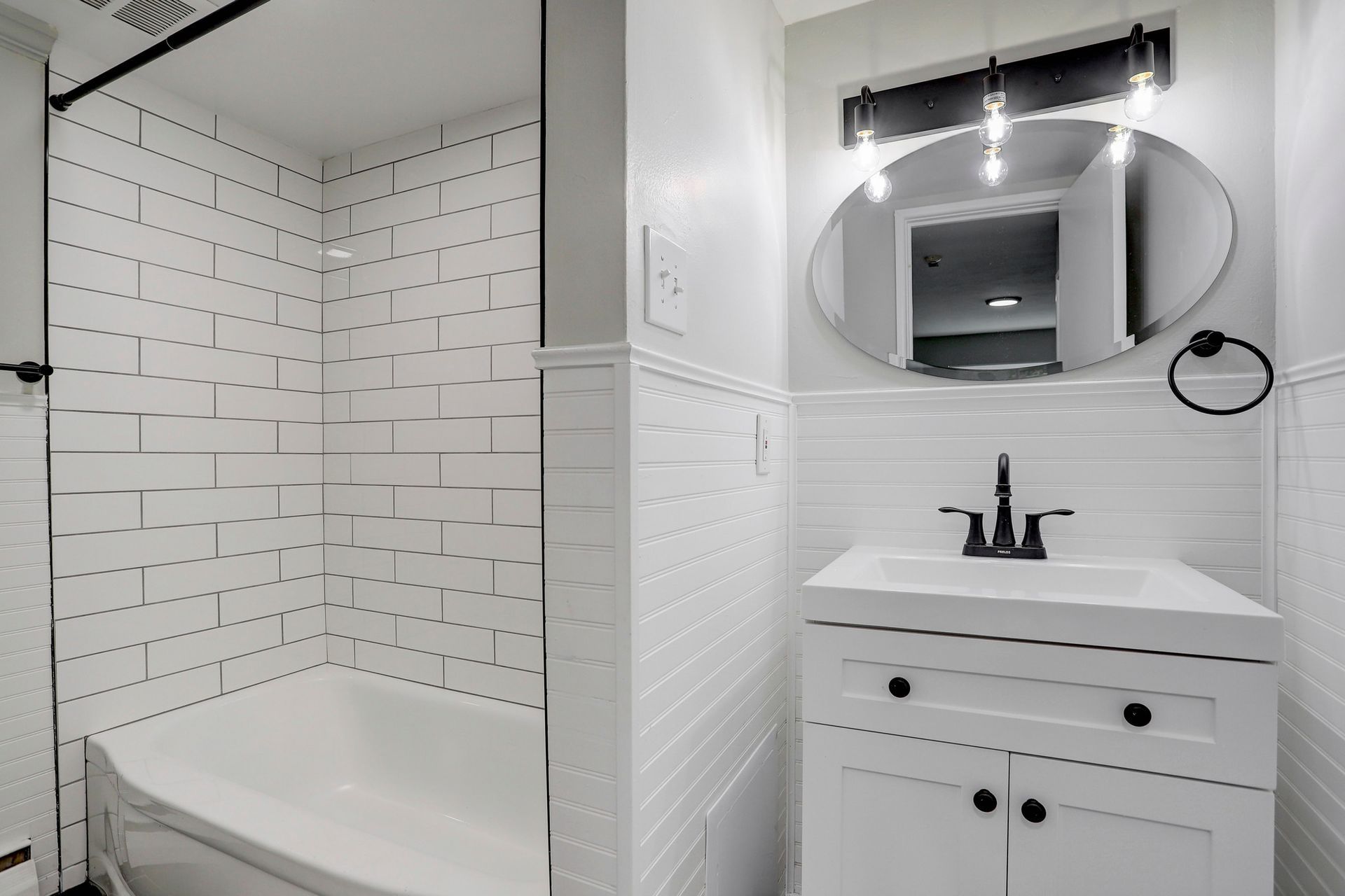 a bathroom with a bathtub , sink and mirror .