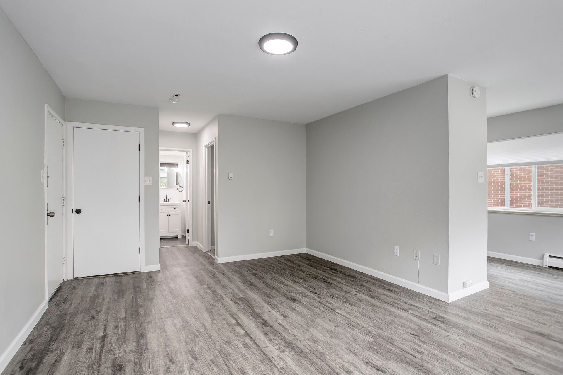 an empty living room with hardwood floors and white walls .