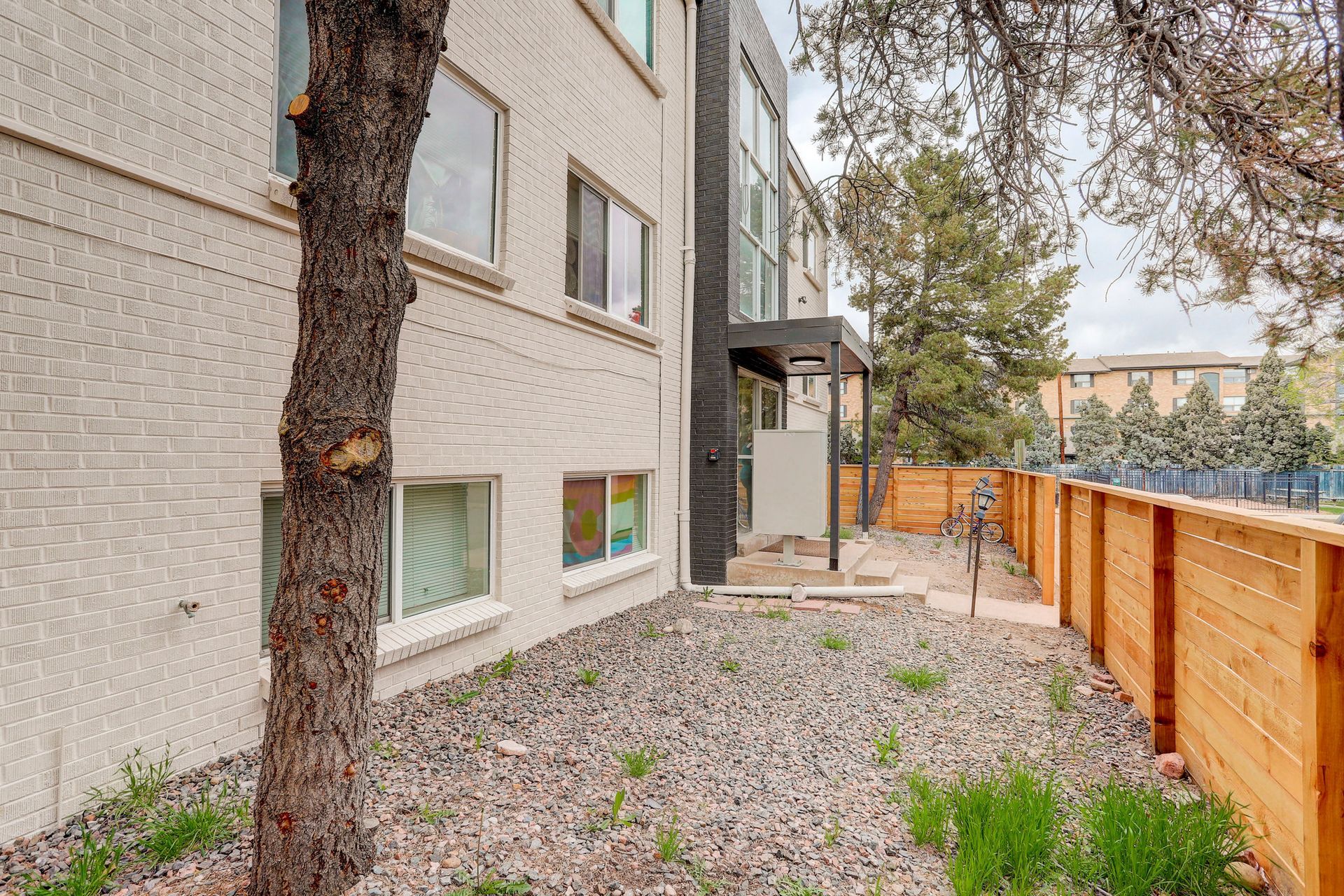 a large apartment building with a wooden fence and a tree in front of it .