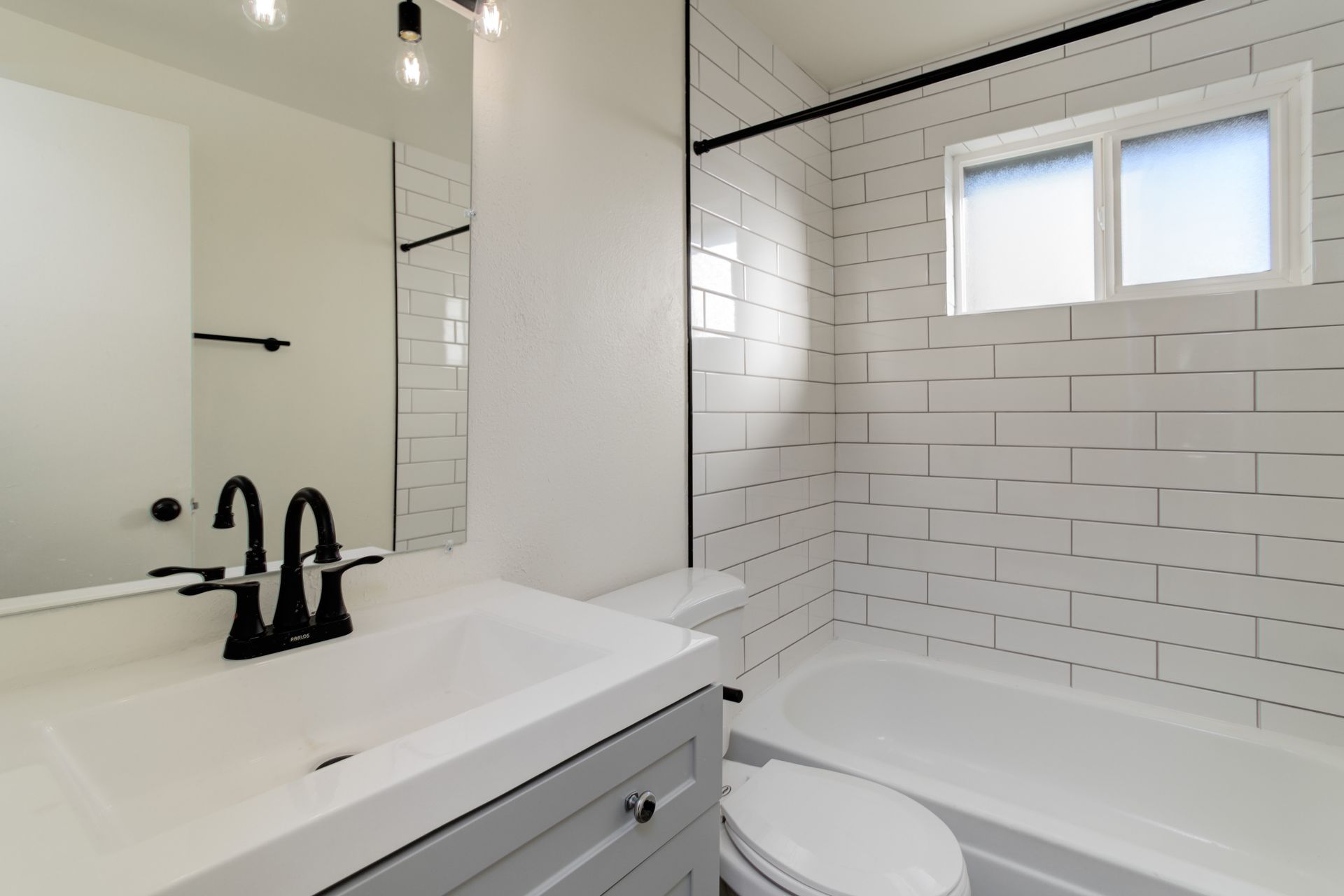 a bathroom with a sink , toilet , tub and mirror .