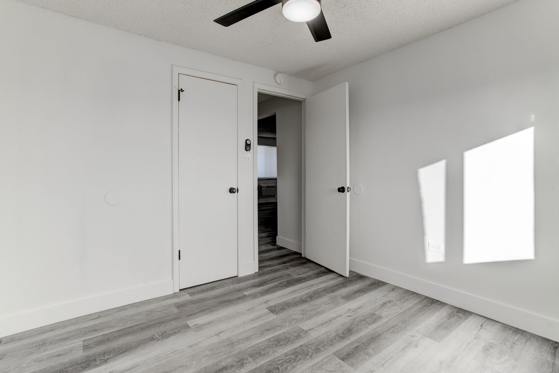 an empty bedroom with a ceiling fan and hardwood floors .