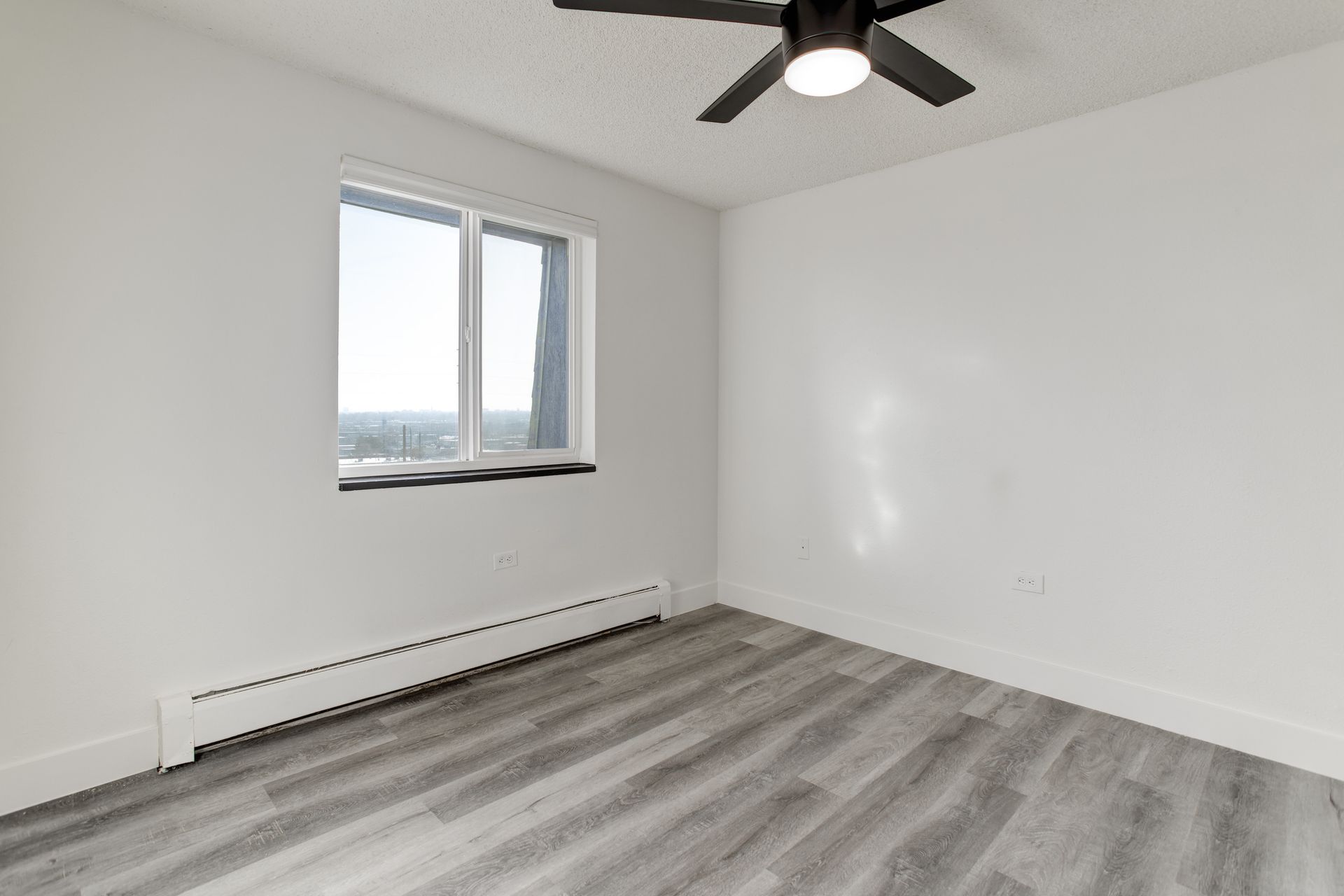 an empty room with a ceiling fan and a window .