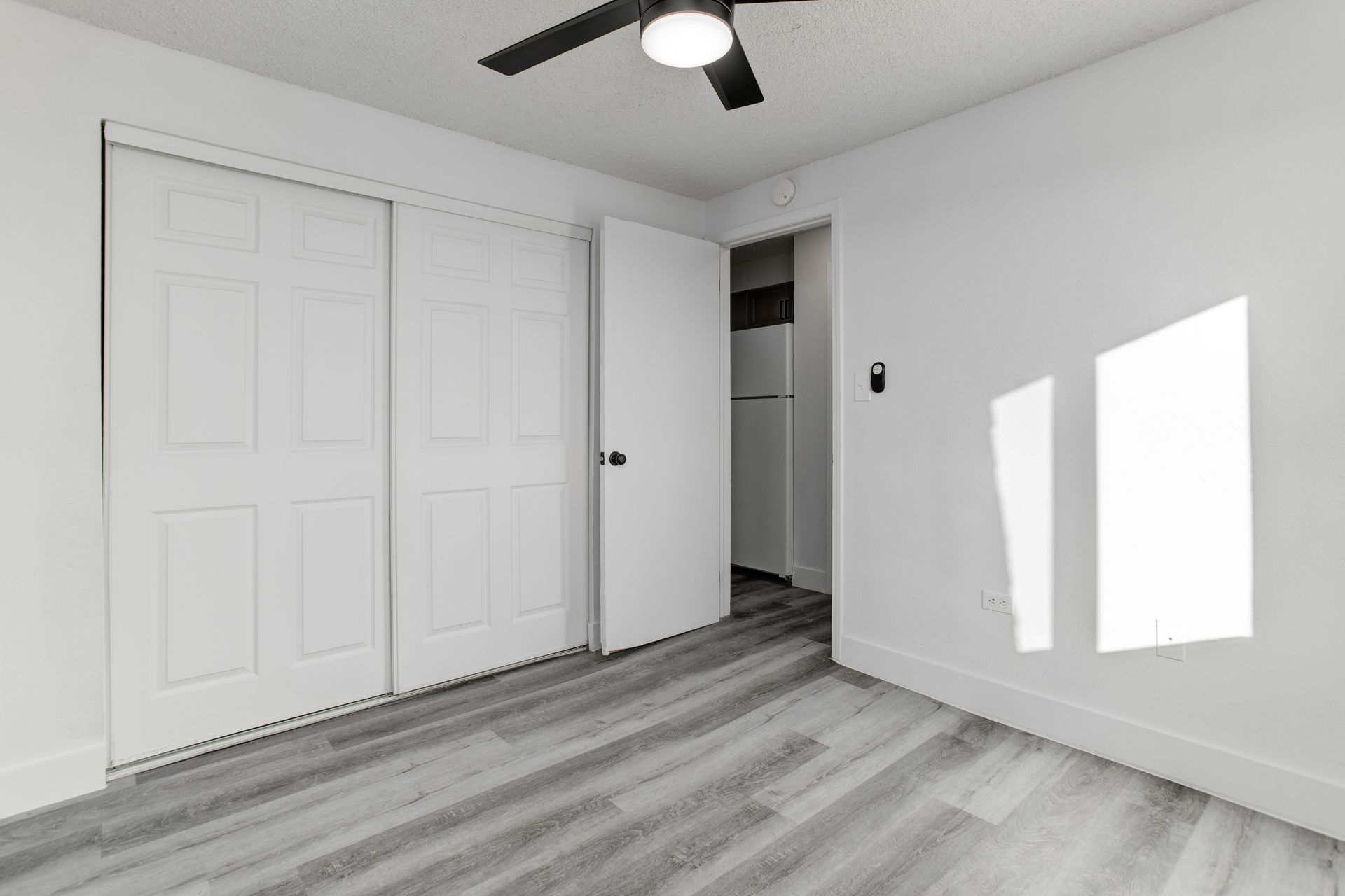 an empty bedroom with a ceiling fan and sliding doors .