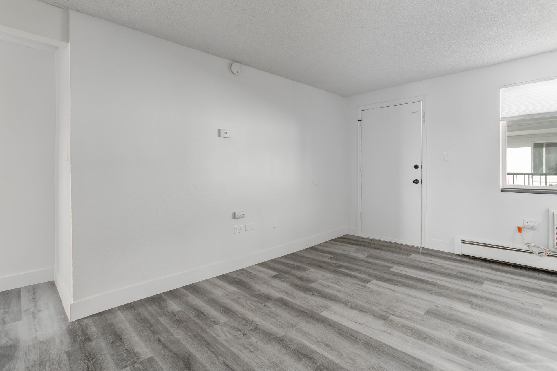 an empty living room with hardwood floors and white walls .
