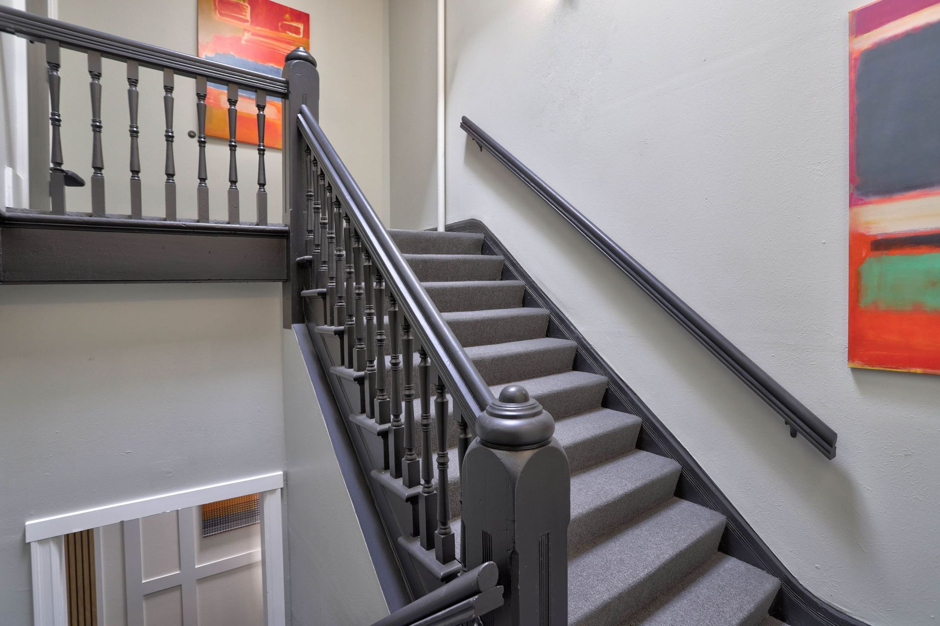 a staircase with a railing and a painting on the wall