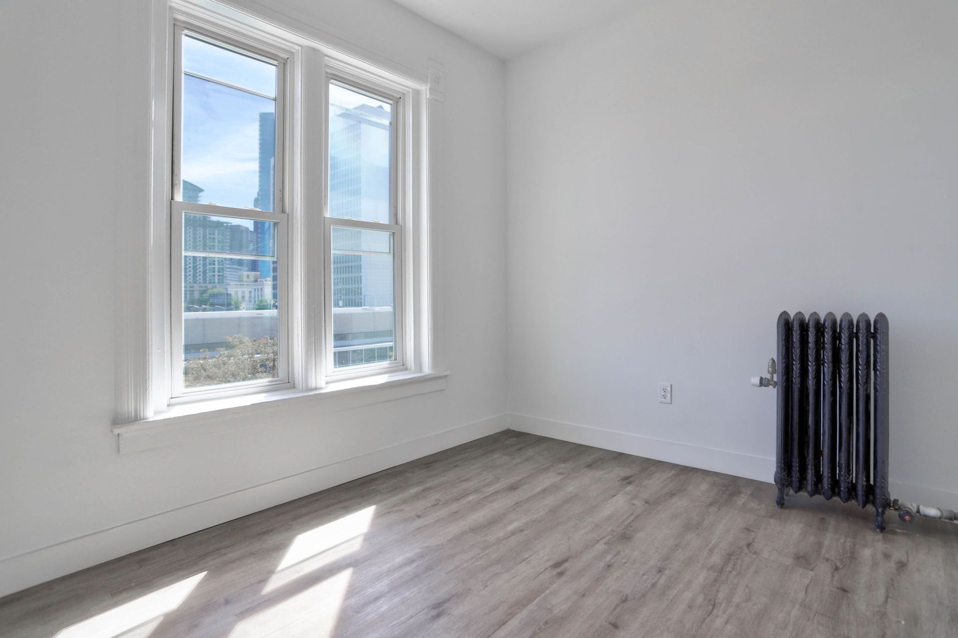 an empty room with two windows and a radiator .