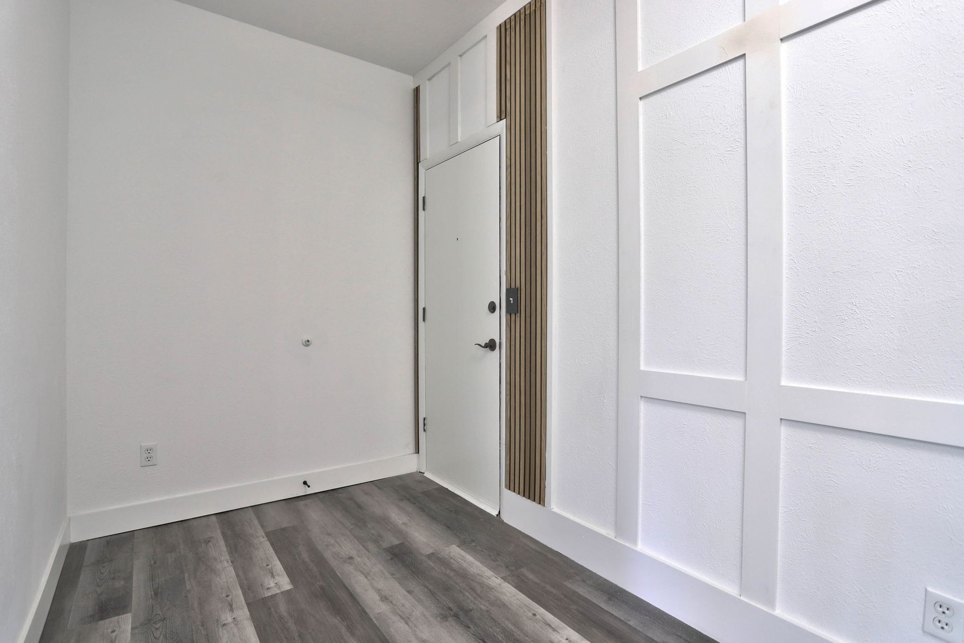 an empty room with hardwood floors and white walls .
