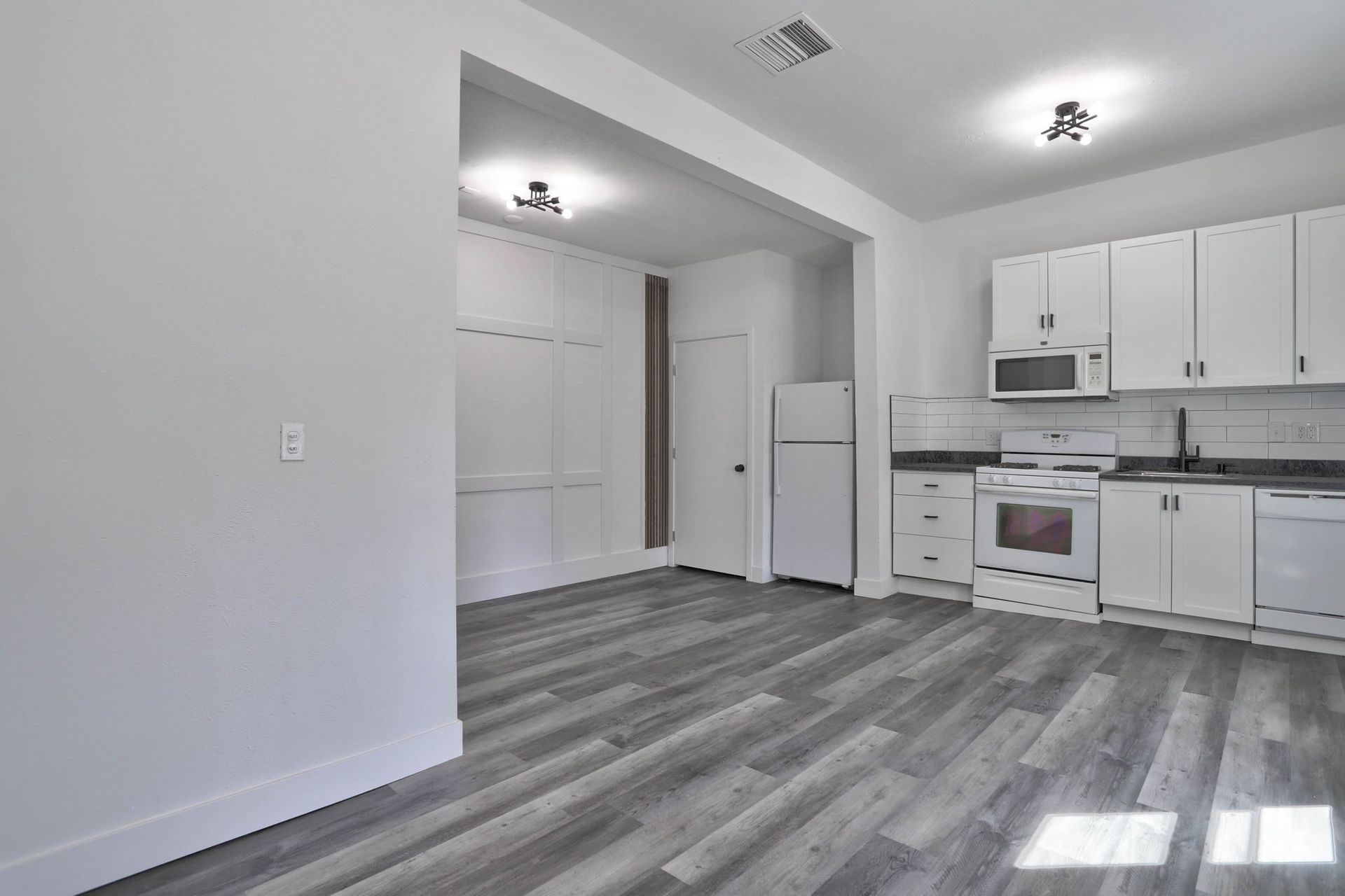 a kitchen with white cabinets , a stove , a refrigerator , and a microwave .