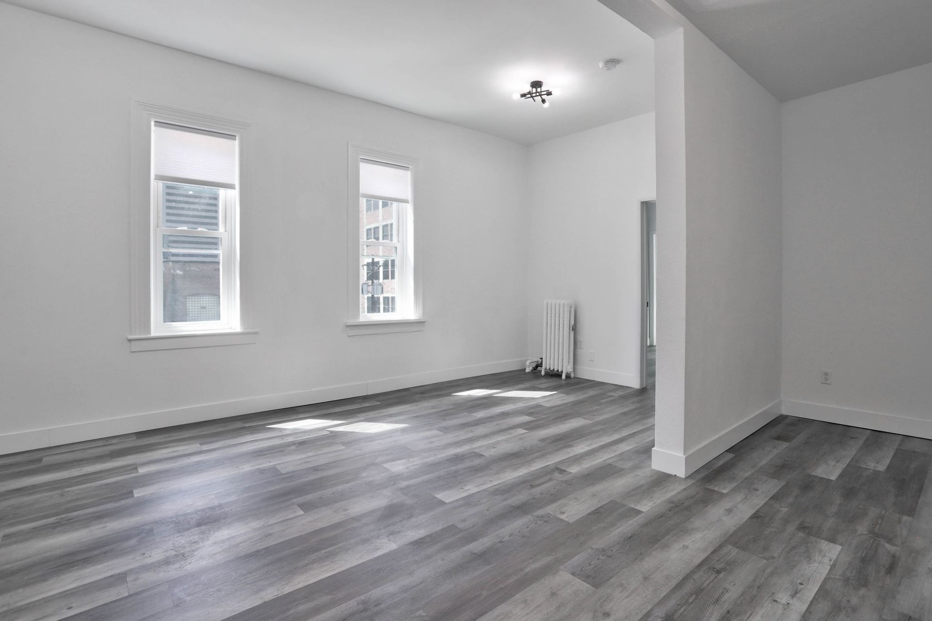 a large empty room with hardwood floors and two windows .