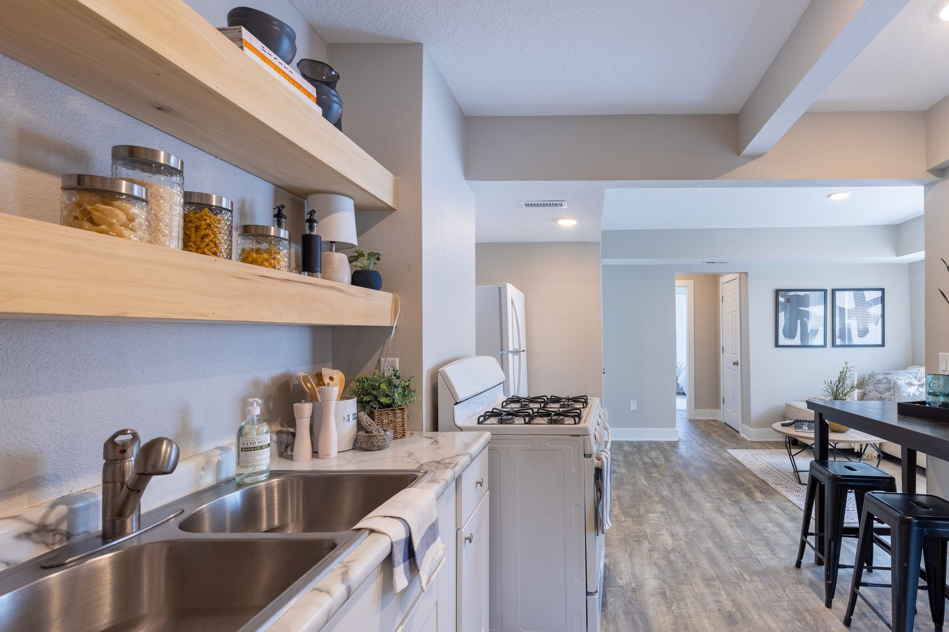 a kitchen with a sink , stove , refrigerator and shelves .