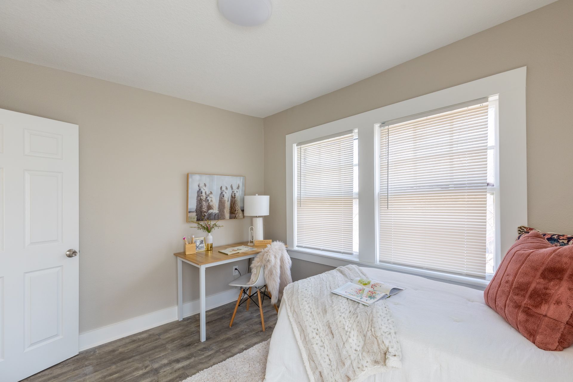 a bedroom with a bed , desk and two windows .