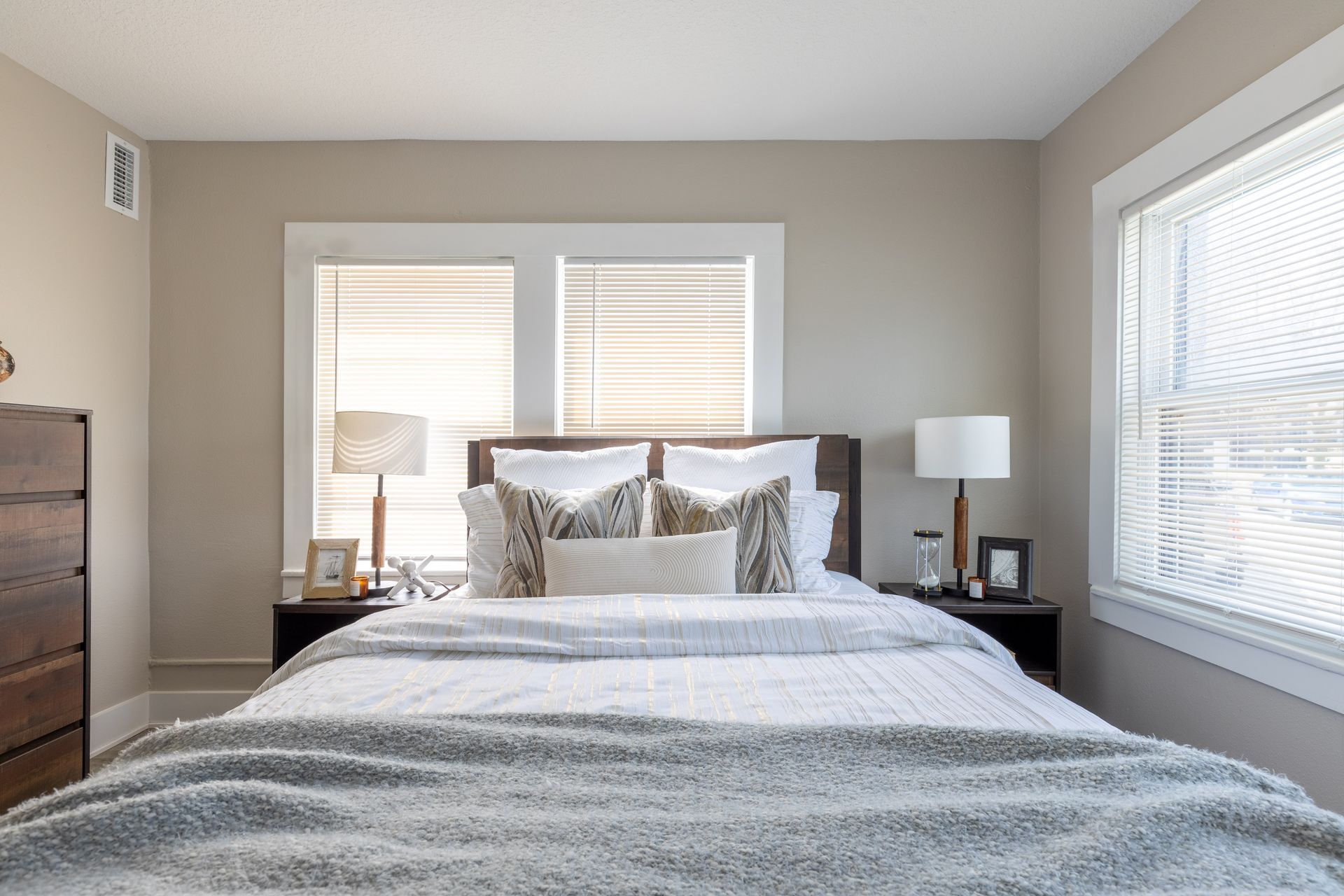 a bedroom with a bed , two lamps , and a window .