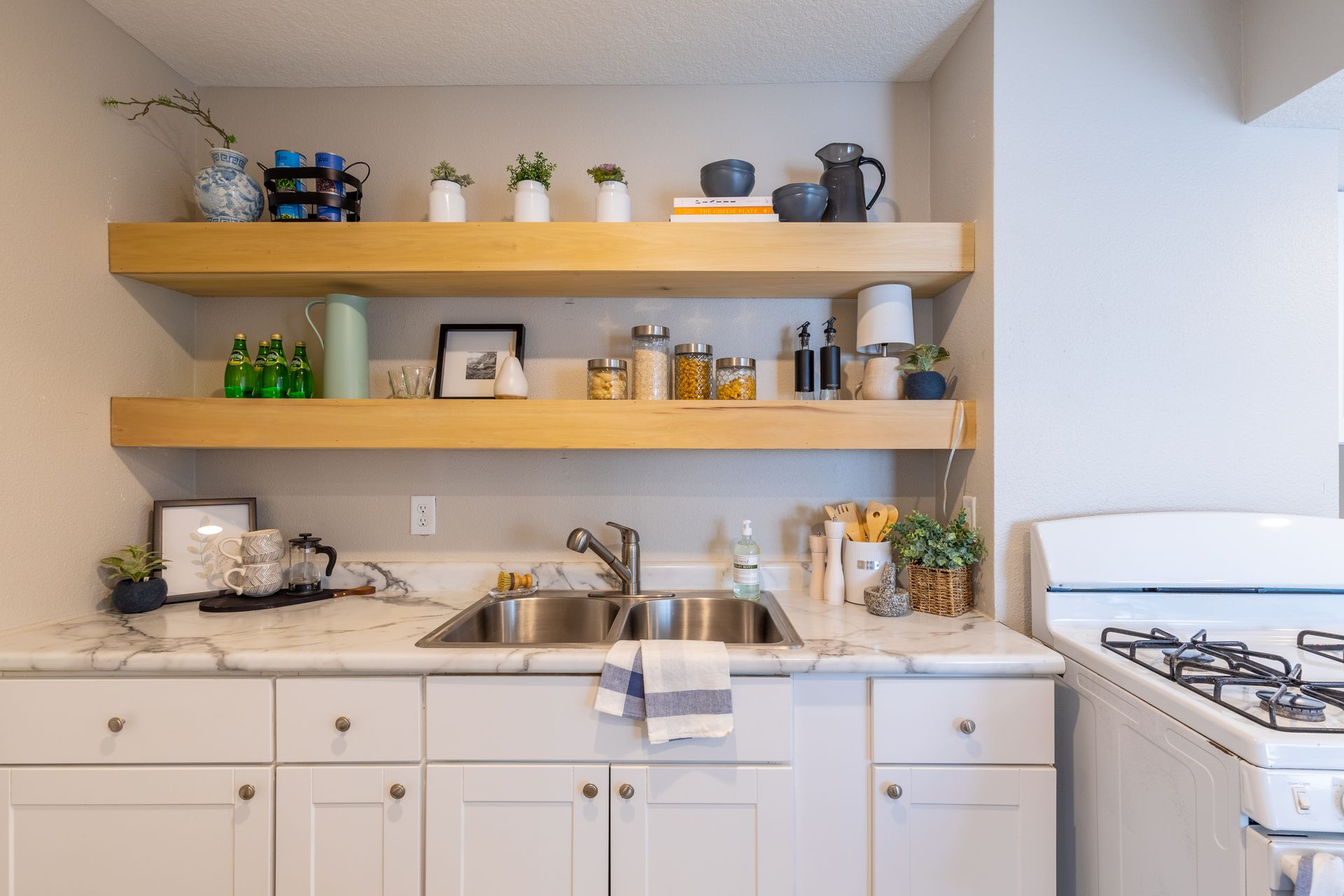 a kitchen with a sink , stove , and shelves .