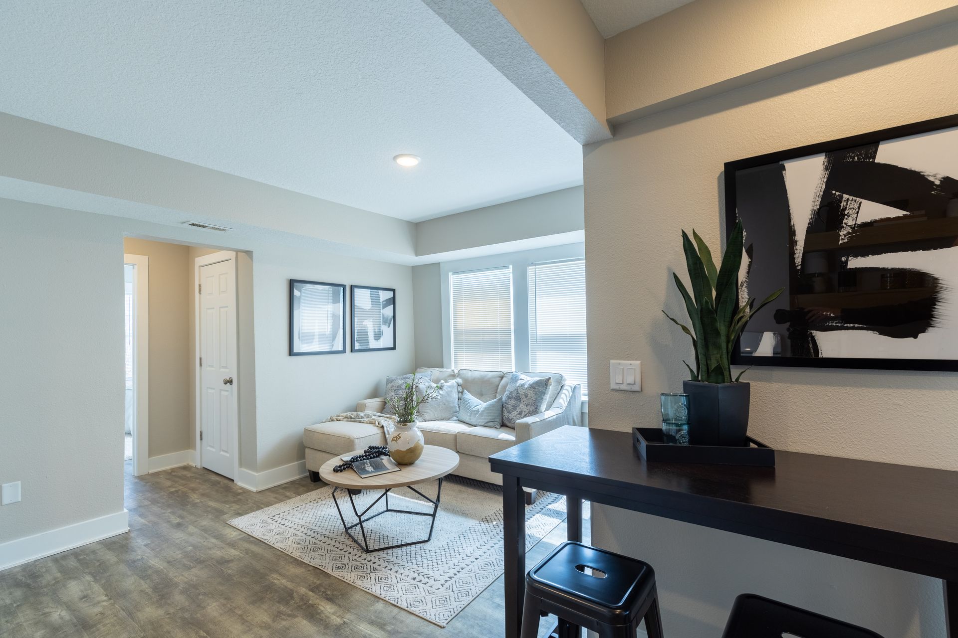 a living room with a couch , table , stools and a picture on the wall .