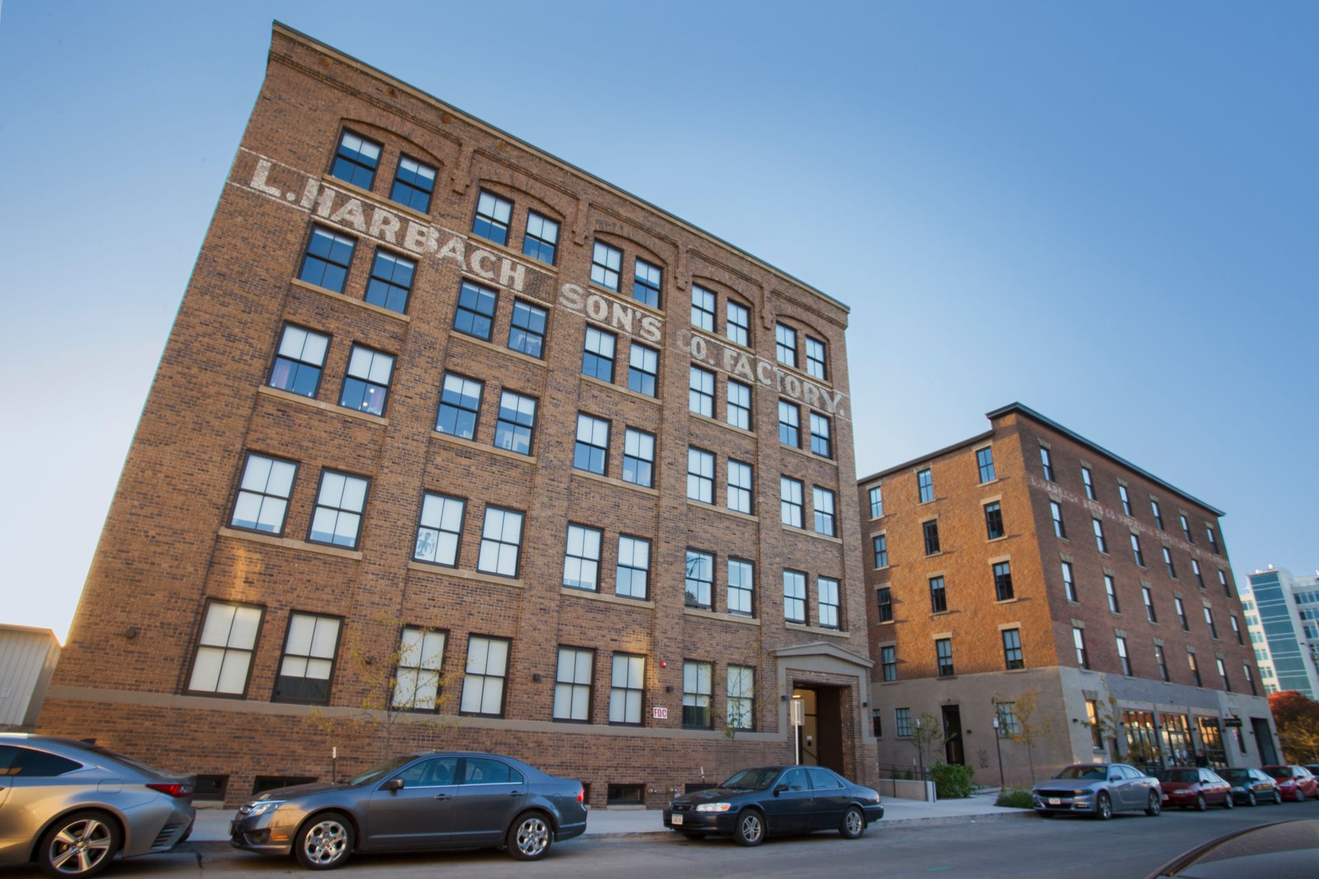 cars are parked in front of a large brick building that says l. harbach sons