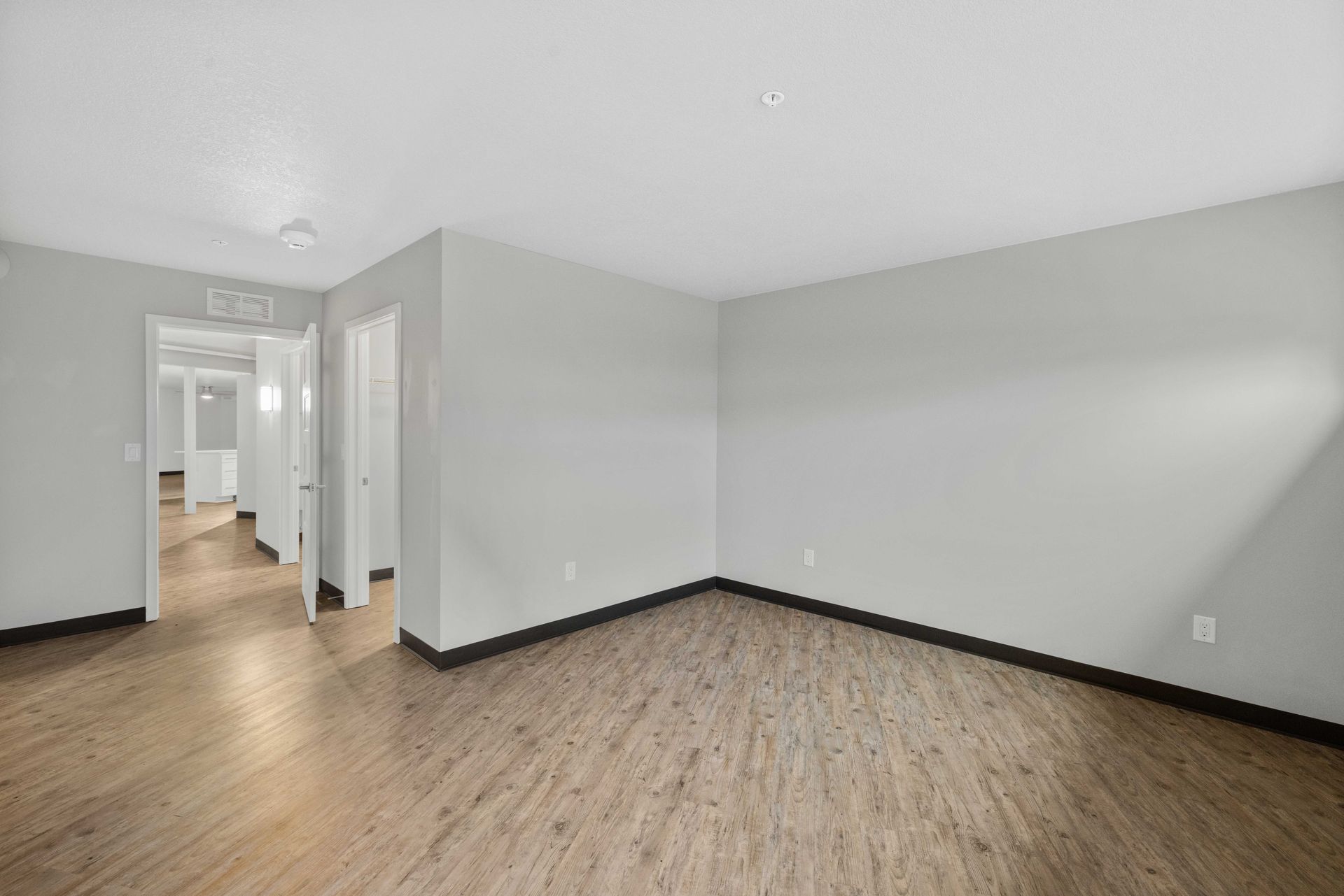 an empty living room with hardwood floors and white walls .