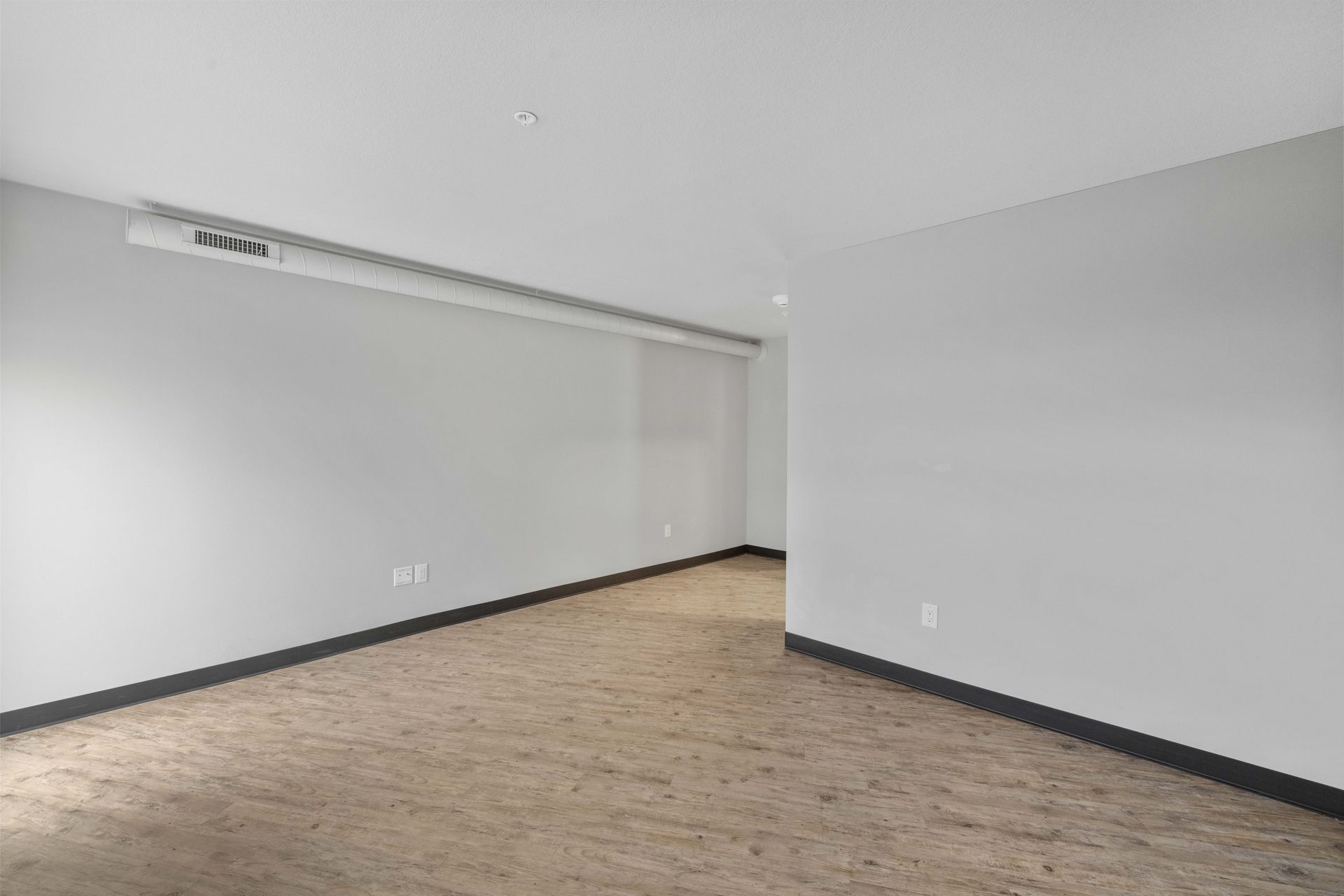 an empty room with a wooden floor and white walls .