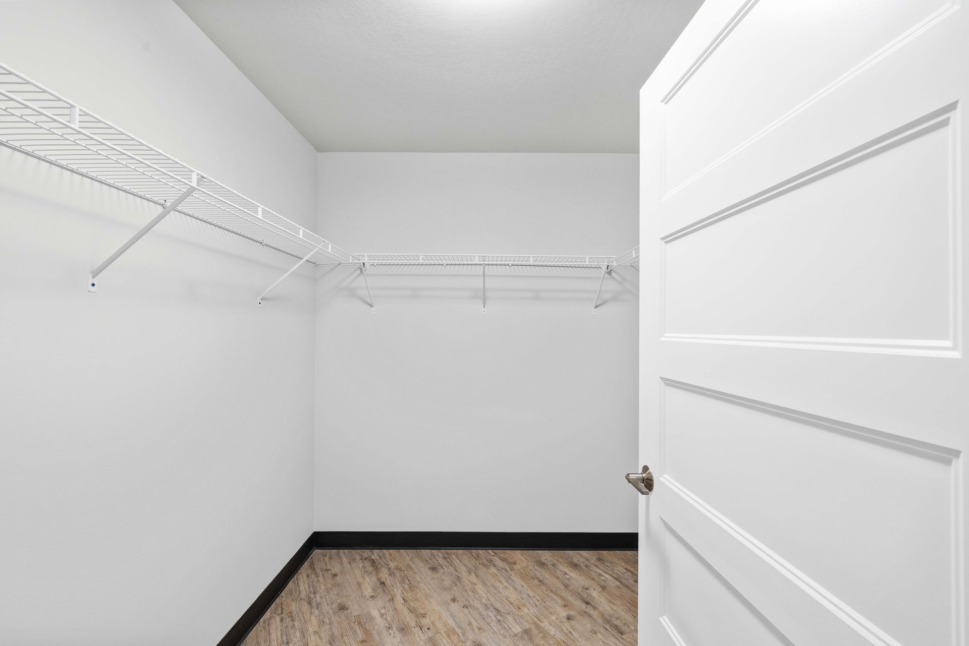 an empty walk in closet with a door open and shelves .